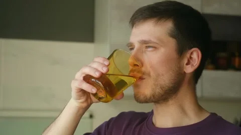 Person enjoying drink water while contemplating sunlight from kitchen window Stock Footage 337547706