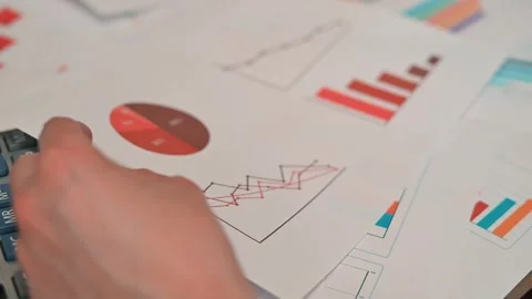 A person examines documents with charts and graphs related to job loss. The 動画素材 338188292