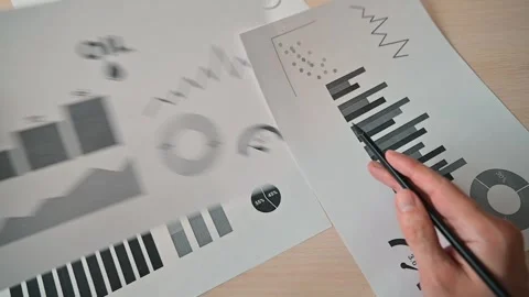 A person examines printed data sheets that display various graphs and charts Видео 338303606