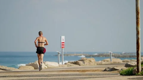 Person exercizing jogging and running on beach promenade in Tel Aviv Israel Stock Footage 312447206