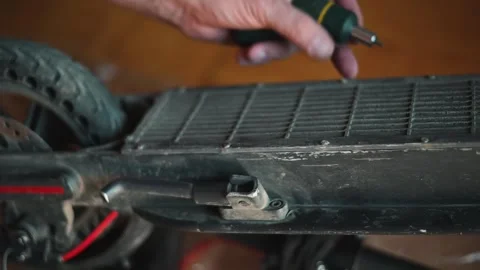 A person fixes an electric scooter using a screwdriver and other tools in a home Stock Footage 338447712