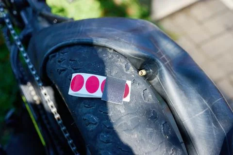 A person is fixing a bicycle tire using a patch and tape. The bike is resting Stock Photos