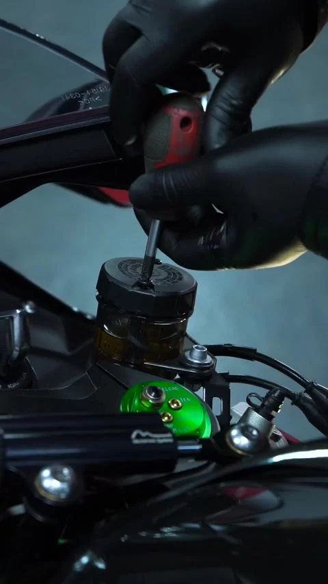 Person fixing motorcycle using screwdriver on vehicles exterior Stock Footage 271379610