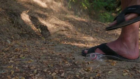 Person in Flip Flops Stepping on Discarded Plastic Litter on Trail Stock Footage 343573655