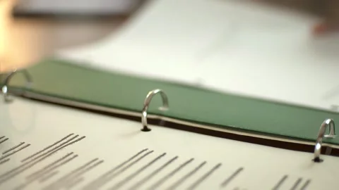 A person flips through pages in a binder, organizing documents. Ideal for Stock Footage 336040946