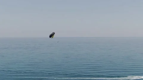 Person flying high with parachute while speed boat towing over Stock Footage 160594441