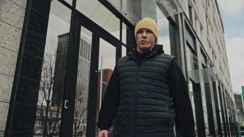 Person with a focused expression wearing a yellow beanie and black puffer vest Stock Footage 274433294