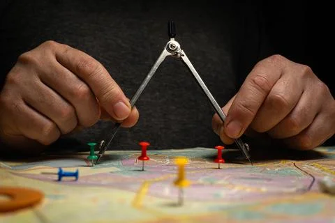 A person is focused on using a compass to create circles on a map. Several co Stock Photos