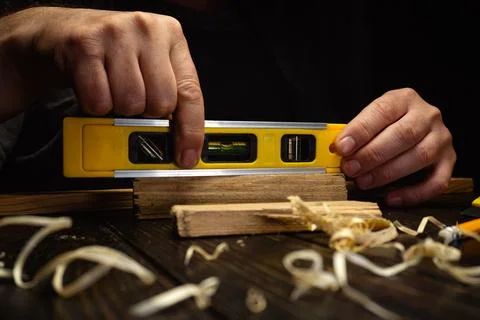 A person is focused on using a level tool to ensure wooden planks are straigh Stock Photos