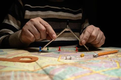 A person focuses on a map, using a compass to mark specific points. Colorfu.. 写真素材