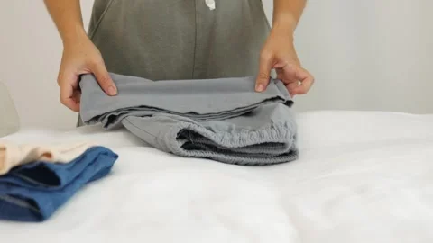 Person folding clothes on bed, home organization, lifestyle Stock Footage 337311339