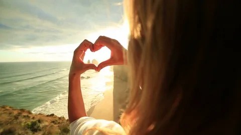 Person frames Twelve Apostles at sunset into heart shape Video stock 76346083