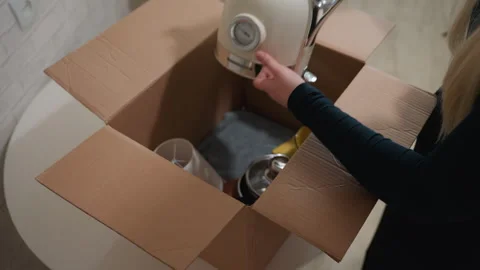 Person gently packing fragile kitchen items for moving. Individual organizing Stock Footage 342055653