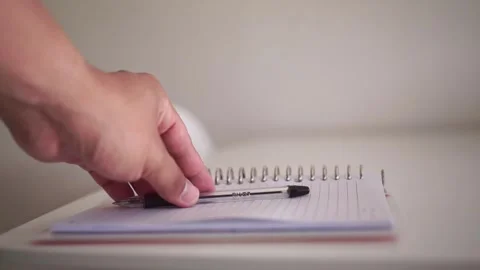 Person gently sets a ballpoint pen on an open notebook, symbolizing task Stock Footage 341378909