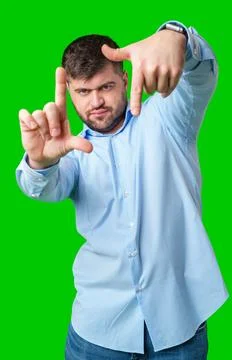 Person gesturing a framing shape with hands in a bright green studio setting Stock Photos