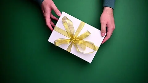 Person with gift box, present with golden ribbon. Top view of hands rotating Stock Footage 208515745