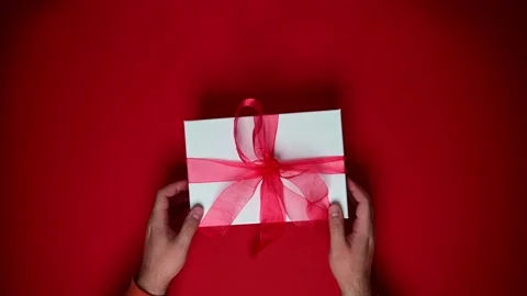 Person with gift box, present with red ribbon. Top view of hands rotating Stock Footage 202178226