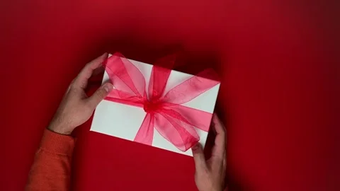 Person with gift box, present with red ribbon. Top view of hands rotating Stock Footage 205241757