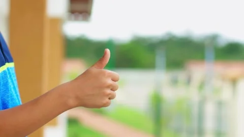 A person is giving a thumbs up gesture while standing on a balcony Stock Footage 309863946