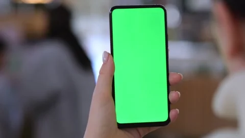 Person grips phone displaying solid green screen Video stock 345710074