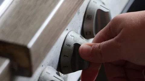Person hand adjusting temperature control knob on stove Stock Footage 334674370