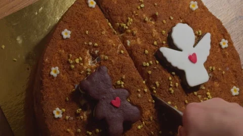 Person hand cuts cake with figures in the form of a bear and angel with red Stock Footage 309015905