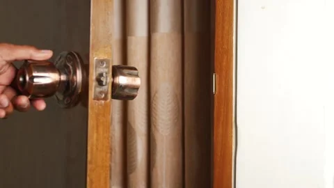 Person hand opening and closing a wooden room door with metal knob in home .. Stockbeeldmateriaal 332474832
