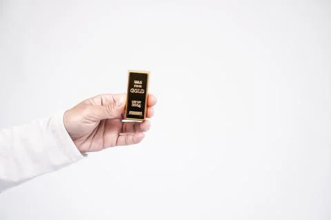 A person hand presenting a single fine gold bullion bar on the left side, l.. Stock Photos