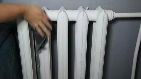 Person hand with ring cleans white cast iron heating radiator with dark cloth 스톡 동영상 329622125