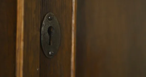 Person by hand turns old key in the keyhole of antique wooden cabinet 库存影片 105663396