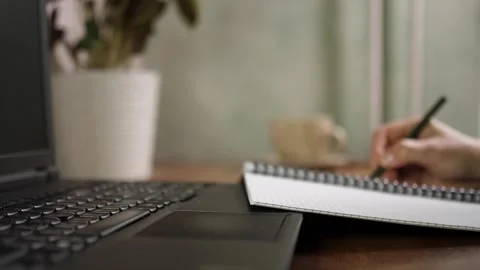 Person hand writing notes with pencil in notepad near laptop close up Video stock 344058170