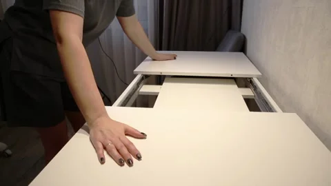 Person hands assemble white folding table in modern home interior, extendable Vídeos de archivo 329621784