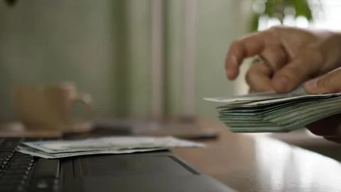 Person hands counting stack of dollar bills on laptop keyboard close up Stock Footage 344058175