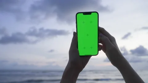 Person hands hold vertical mobile phone with green screen against background Stock Footage 220875413