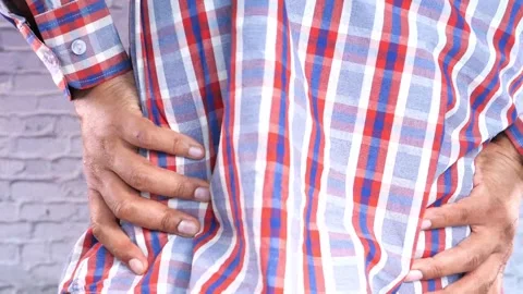 Person with hands on lower back showing pain and discomfort. Stock Footage 332579600