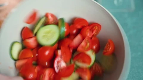 A person with hands is preparing a fresh salad by chopping tomatoes and Stock-Footage 338290342