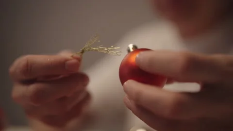 Person hands preparing small festive red Christmas bauble with golden string Stock Footage 323348163