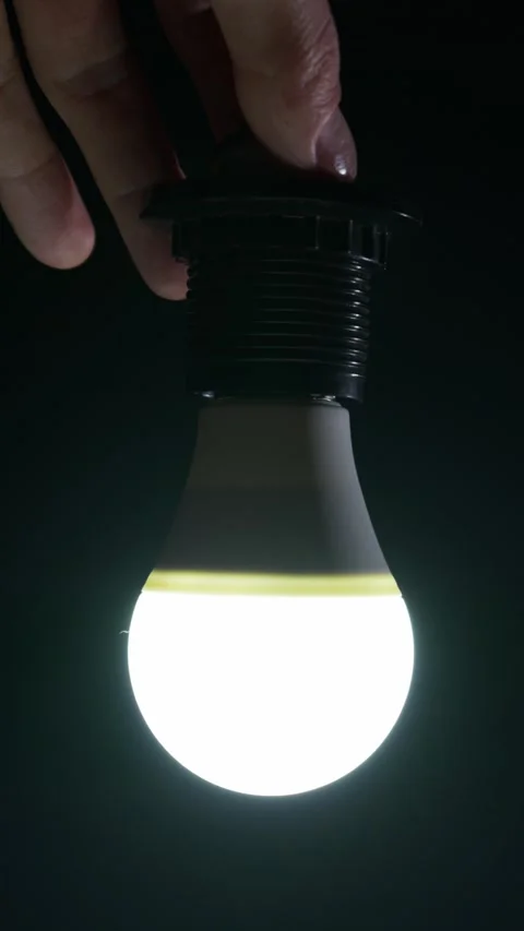 Person Hands Screwing Led Light Bulb Into Socket in Cinematic Low Key Lighting Stock Footage 334136522