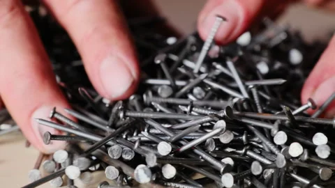 Person hands sort through large pile of dark metallic nails Stock Footage 316157627