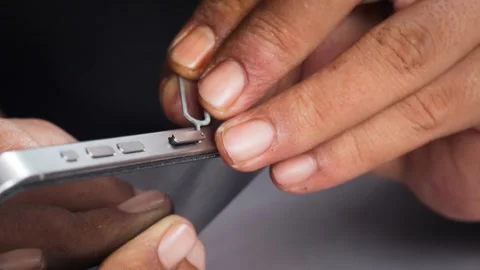Person hands using an ejector tool to open the SIM card tray slot Stock Footage 348910172