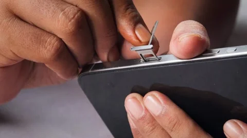 Person hands using an ejector tool to open the SIM card tray slot Stock Footage 348910173