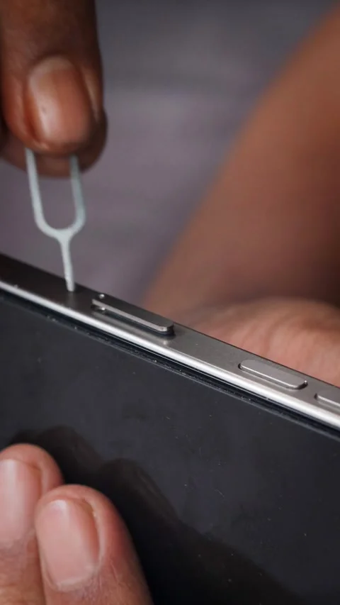 Person hands using an ejector tool to open the SIM card tray slot Stock Footage 348910185