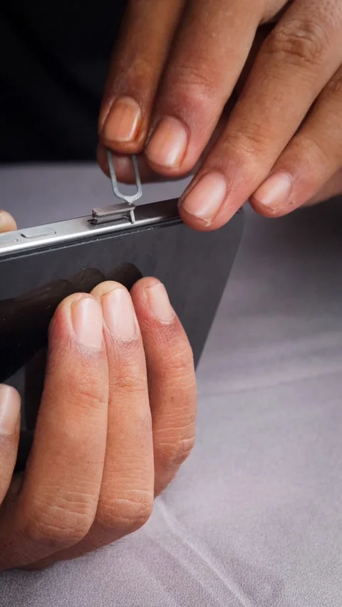 Person hands using an ejector tool to open the SIM card tray slot Stock Footage 348910225
