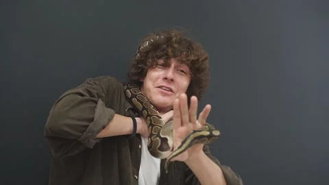 A person has a panic attack with a snake in his hands, a confused guy can't move Stock Footage 157636910