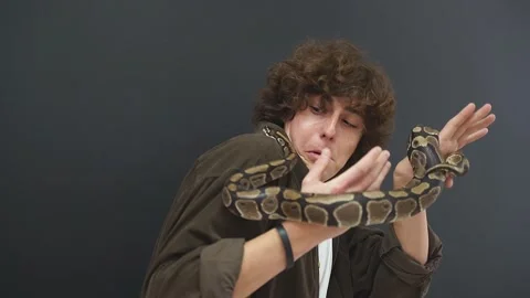 A person has a panic attack with a snake in his hands, a confused guy can't move Stock Footage 158142970