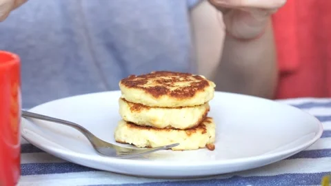 Person having rustic breakfast of apple pancakes and honey with fork	 Stock Footage 134022949