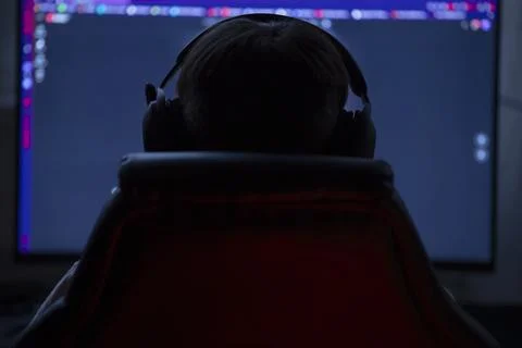 Person with Headphones Coding at Computer in Dark Background 스톡 사진