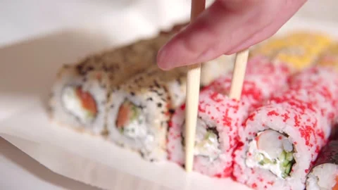 A person with the help of a hand and disposable chopsticks takes sushi Stock Footage 162500667