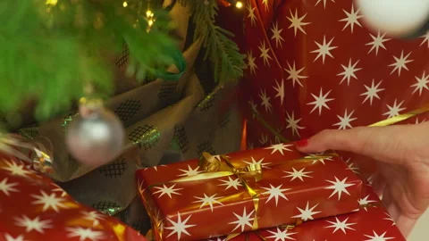 Person hides red present box under decorated Christmas tree Stock Footage 214453248