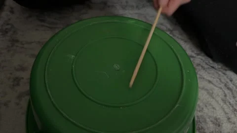 Person hitting plastic container with stick creating sound at home, improvised Stock Footage 337105707